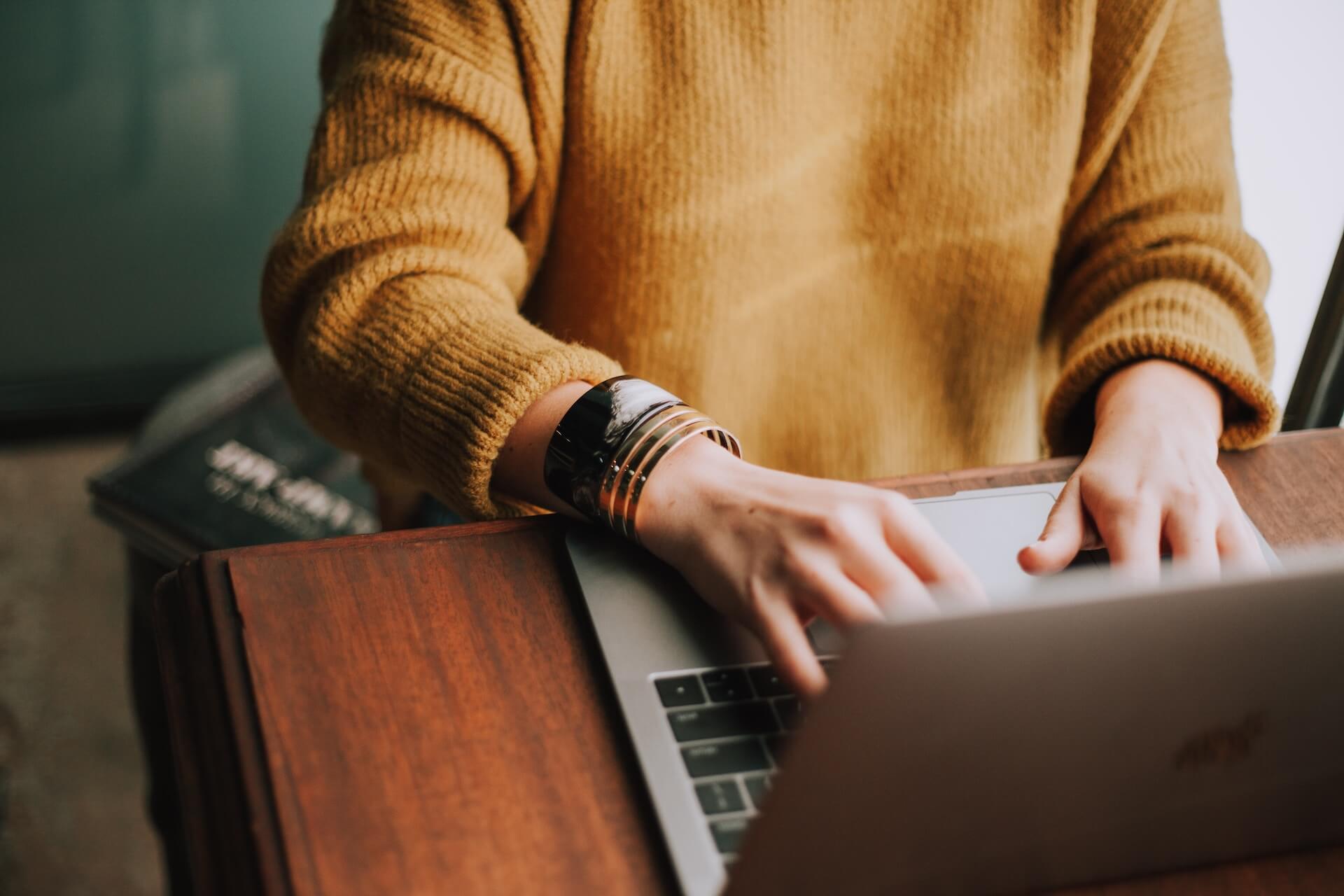 person in jumper working on laptop